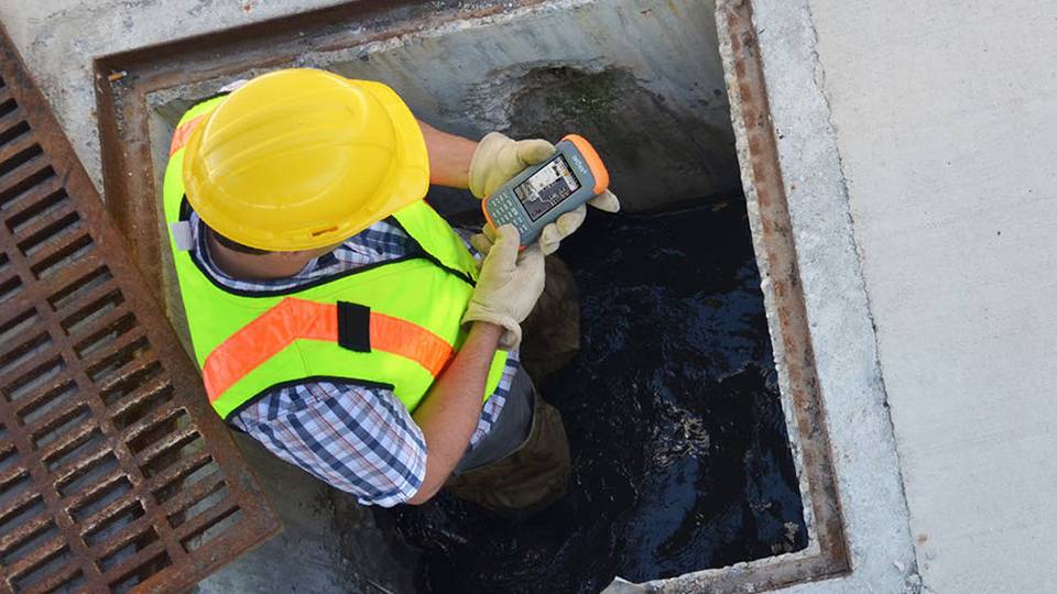 Man in utility drain with Juniper Handheld device