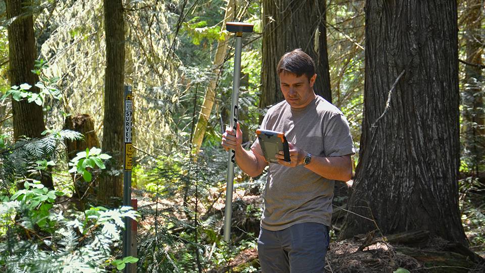 Mann im Wald benutzt Mesa und Geode, um mit der Software Uinta den Standort von Naturressourcen zu kartieren